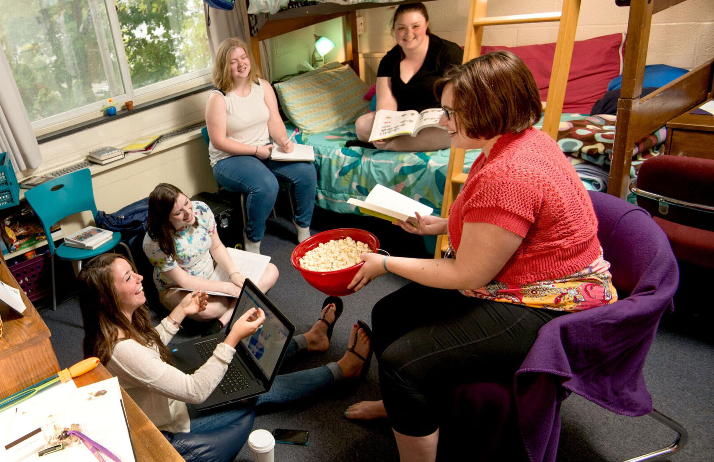 A group of female students hang out and enjoy some popcorn in an Anderson Hall dorm room